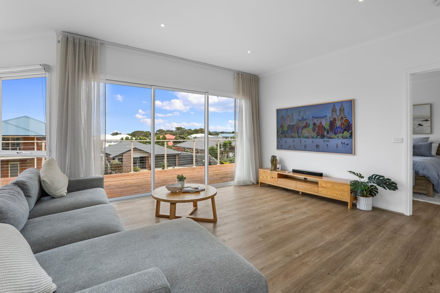 Spacious upstairs lounge with a grey sofa and deck access