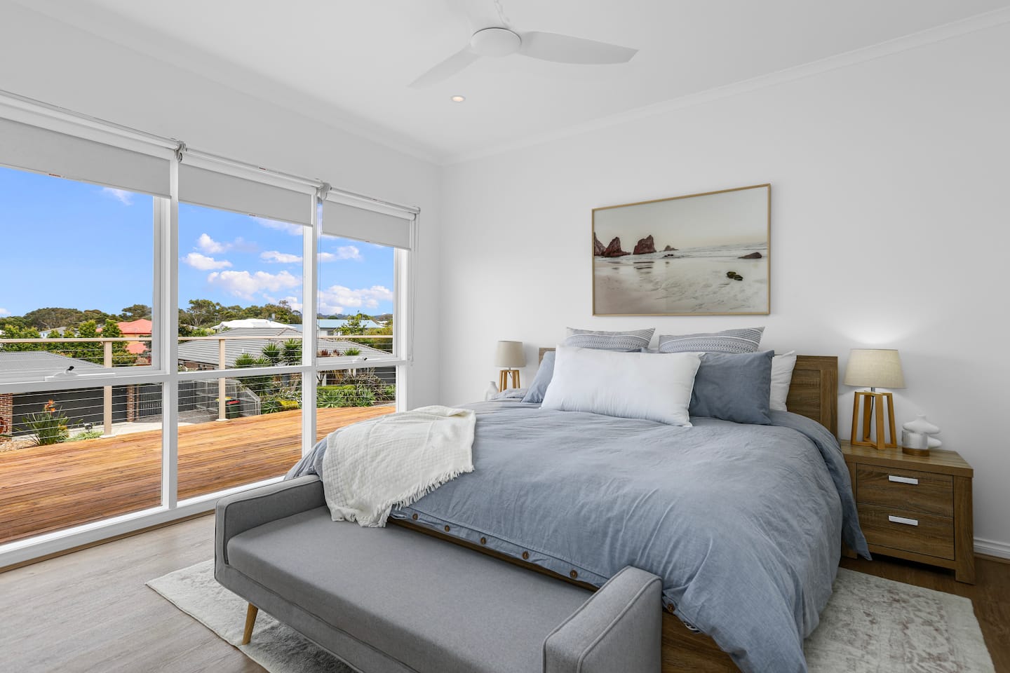 King bedroom with large windows and a soft blue bedspread